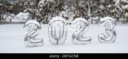 Winterbanner mit silbernen Zahlen Silberjahr 2023 im Schnee auf dem Hintergrund von schneebedeckten Bäumen und Büschen mit Kopierbereich. Stockfoto