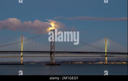 In Blue Hour, Firth of Forth, Schottland, Großbritannien, geht ein Vollmond über die Brücken Queensferry Crossing und Forth Road Stockfoto