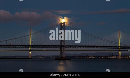 In Blue Hour, Firth of Forth, Schottland, Großbritannien, geht ein Vollmond über die Brücken Queensferry Crossing und Forth Road Stockfoto