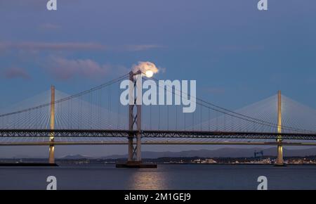 In Blue Hour, Firth of Forth, Schottland, Großbritannien, geht ein Vollmond über die Brücken Queensferry Crossing und Forth Road Stockfoto