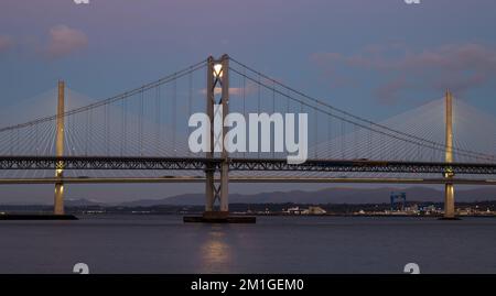 In Blue Hour, Firth of Forth, Schottland, Großbritannien, geht ein Vollmond über die Brücken Queensferry Crossing und Forth Road Stockfoto