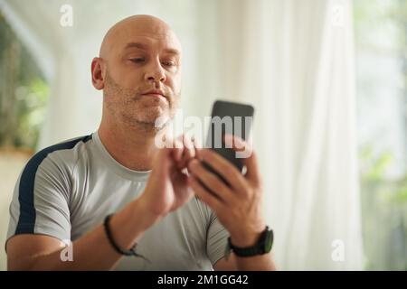 Ein erwachsener Mann beantwortet eine SMS von einem Freund oder Familienmitglied Stockfoto