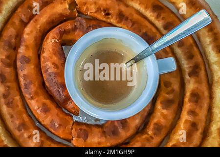 Mit Milch geschnittener Kaffee, in der Mitte einer Portion Churros Stockfoto