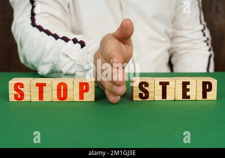 Geschäftskonzept. Ein Mann trennt die Würfel mit der Inschrift - STOPP oder STUFE Stockfoto