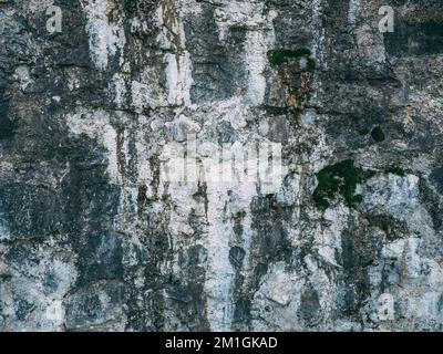 Oberfläche der verwitterten alten Steinwand mit Schimmel und Flecken bedeckt. Stockfoto