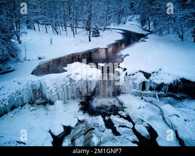 DJI-Drohnenfoto eines gefrorenen Keila-Wasserfalls in Estland im Winter, gefrorener Fluss und Park Stockfoto