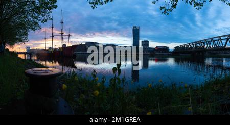 Sonnenuntergang an der Weser in Bremen mit Reflexion der Bürogebäude der Überseestadt Stockfoto