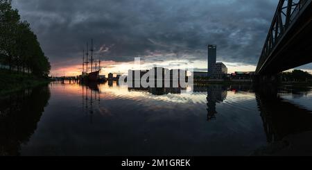 Sonnenuntergang an der Weser in Bremen mit Reflexion der Bürogebäude der Überseestadt Stockfoto