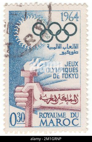 MAROKKO - 1964. September 22: Eine blaue, dunkelgrüne und rotbraune Briefmarke mit 30 Centimes, die die olympische Fackel darstellt. Olympische Spiele 18., Tokio, 10.-25. Oktober. Die Olympischen Sommerspiele 1964, offiziell die Spiele der XVIII. Olympiade und allgemein bekannt als Tokio 1964, waren eine internationale Multisport-Veranstaltung, die vom 10. Bis 24. Oktober 1964 in Tokio, Japan, stattfand. Tokio wurde die Veranstaltung der Olympischen Sommerspiele 1940 verliehen, doch diese Auszeichnung wurde aufgrund der japanischen Invasion Chinas an Helsinki vergeben, bevor sie schließlich aufgrund des Zweiten Weltkriegs abgesagt wurde Stockfoto