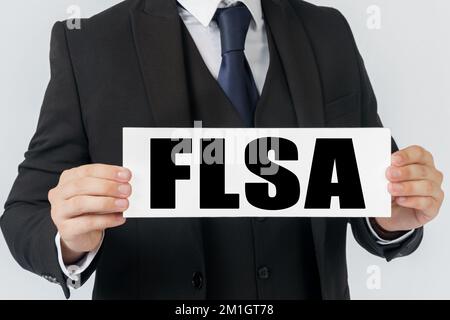 Geschäfts- und Finanzkonzept. Ein Geschäftsmann hält ein Schild in den Händen, auf dem FLSA steht Stockfoto