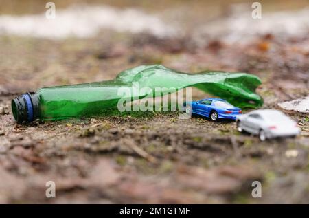 Umweltkonzept. Die Leute fahren im Urlaub mit ihren Autos durch einen Bogen aus einer Plastikflasche - ein Symbol der Verschmutzung. Stockfoto