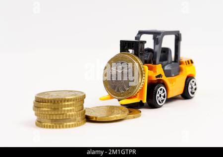 Business- und Economy-Konzept. Ein Spielzeuglader transportiert Münzen. Isoliert auf weißem Hintergrund. Stockfoto