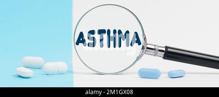 Medizin und Gesundheitskonzept. Auf blauem und weißem Hintergrund gibt es Pillen und eine Lupe, in der es steht - ASTHMA Stockfoto