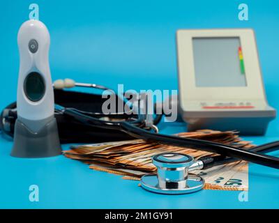 Medizinisches Stethoskop, Thermometer und Banknoten auf blauem Hintergrund. Nahaufnahme. Stockfoto