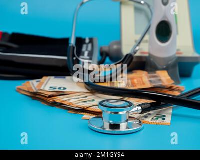 Medizinisches Stethoskop, Thermometer und Banknoten auf blauem Hintergrund. Nahaufnahme. Stockfoto