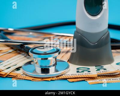 Medizinisches Stethoskop, Thermometer und Banknoten auf blauem Hintergrund. Nahaufnahme. Stockfoto