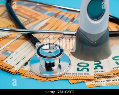 Medizinisches Stethoskop, Thermometer und Banknoten auf blauem Hintergrund. Nahaufnahme. Stockfoto