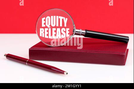 Geschäfts- und Finanzkonzept. Auf weißem und rotem Hintergrund ein Notizbuch, ein Stift und eine Lupe, in der sich die Aufschrift "Equity Release" befindet Stockfoto