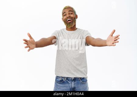 Komm her und umarme dich. Ein netter Kerl, der sich zum Kuscheln die Hände ausstreckt, begrüßt Sie, steht in lässiger Kleidung auf weißem Hintergrund Stockfoto