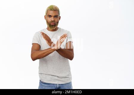 Der Mann sieht besorgt aus, zeigt Stopp, unterbindet Gesten, pausiert, steht über weißem Hintergrund Stockfoto