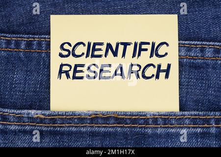 Wirtschafts- und Bildungskonzept. Aus einer Jeansentasche ragt ein Papier mit der Aufschrift "Scientific Research" Stockfoto