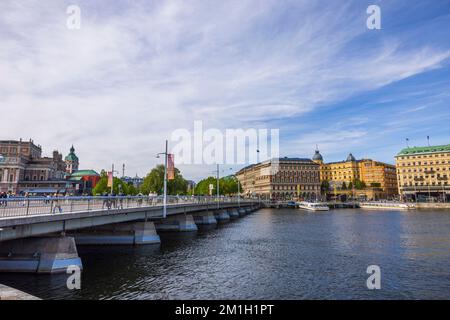 Wunderschöner Blick auf die Stadtlandschaft von Stockholm. Menschen, die auf einer Brücke über den Fluss laufen. Schweden. Stockholm. 05.18.2022. Stockfoto