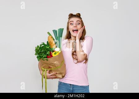 Überraschte weißhäutige Vegetarierin hielt eine Papiertüte mit Lebensmitteln in der Hand Stockfoto