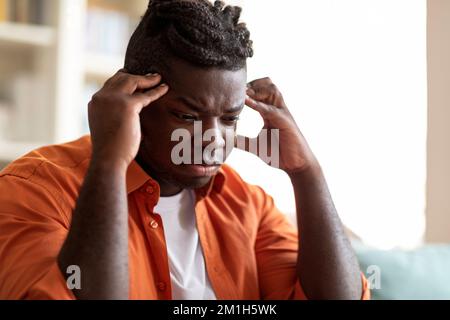 Gestresster junger afroamerikanischer Mann mit starken Kopfschmerzen Stockfoto