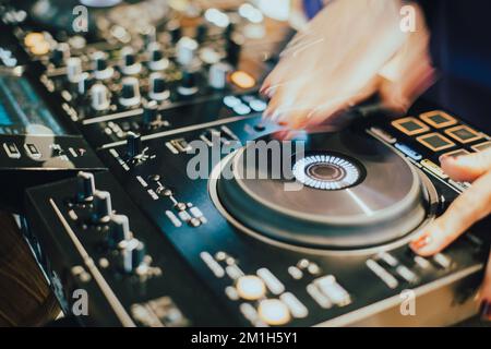 DJ spielt Live-Set und mischt Musik auf der Plattenkonsole auf der Bühne im Nachtclub. Disc Jockey hat einen Soundmixer auf einer Club-Party. DJ-Mixer (Forts. Stockfoto