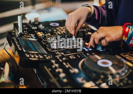DJ spielt Live-Set und mischt Musik auf der Plattenkonsole auf der Bühne im Nachtclub. Disc Jockey hat einen Soundmixer auf einer Club-Party. DJ-Mixer (Forts. Stockfoto