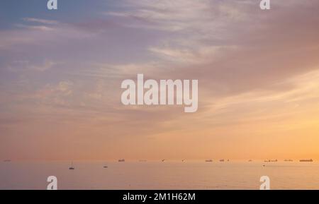 Majestätischer Sonnenuntergang über dem Wasser, viele verschiedene Schiffe und Yachten in einem Meer Stockfoto