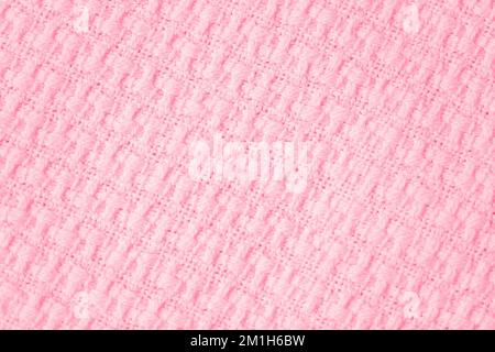 Gestricktes Überwurf-Material Hintergrund in trendigen Farben des Jahres 2023 Viva Magenta, maschinell gestrickte Struktur. Leichte Nahaufnahme der Bettdecke Stockfoto