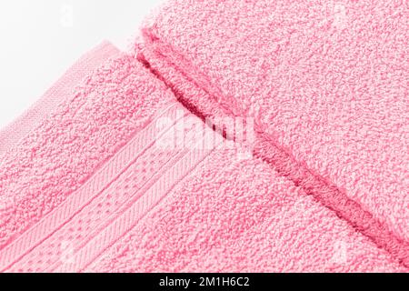 Gefaltete Badetücher oder Handtücher in trendigen Farben des Jahres 2023 Viva Magenta auf weißem Hintergrund. Nahaufnahme der Textur, Kopierbereich Stockfoto