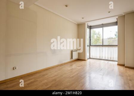 Ein leeres Zimmer mit Wänden voller Spuren von den alten Möbeln und einem Erkerfenster mit Vorhängen unten Stockfoto