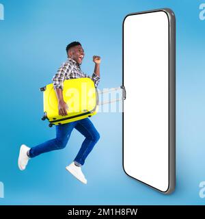 Aufgeregter junger Schwarzer, der mit einem leuchtenden Koffer am Telefon springt Stockfoto