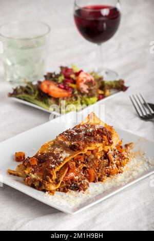 Portion Lasagne auf einem weißen Teller Stockfoto