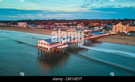 Ruhiges Morgenlicht über dem alten Pier, bedeckt von einer Drohne über dem Meer mit Blick auf den Strand und die Stadt Stockfoto