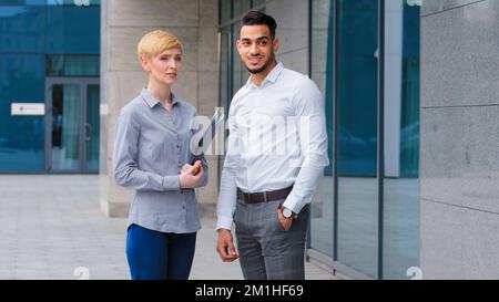 Multiethnisches Paar arabisch-indischer Geschäftsmann und kaukasische Frau halten Ordner zwei Kollegen Partner stehen im Freien und machen Pause bei der Arbeit Stockfoto