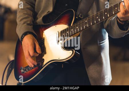 Nahaufnahme eines Gitarristen, der auf einer Bassgitarre spielt, Konzeptstudio einer Musikband. Hochwertiges Foto Stockfoto