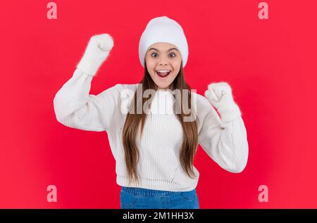 Überraschtes Teenager-Mädchen in warmer Winterstrickkleidung, Pullover und Handschuhe im Studio. Ein junges Wintermädchen Stockfoto