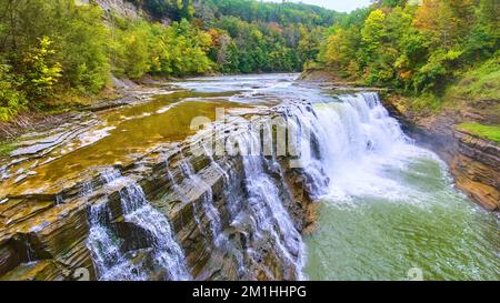 Aus nächster Nähe sehen Sie den wunderschönen Wasserfall, der die Klippen mit bunten Wäldern erodiert Stockfoto