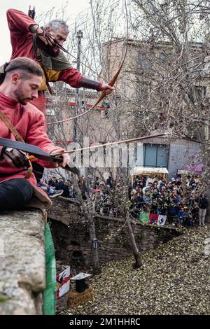 Zwei Bogenschützen in historischen Kostümen bereiten sich darauf vor, während der mittelalterlichen Feste in Vic, einer antiken Stadt in Katalonien, Spanien, ihren Bogen zu schießen. Stockfoto