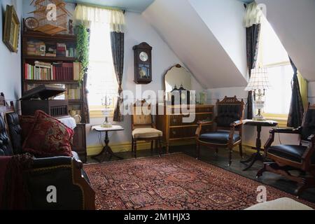 Eastlake Sofa und Sessel mit antiken Möbeln im Zimmer im Obergeschoss in einem alten Haus im viktorianischen Landhausstil aus dem Jahr 1904. Stockfoto