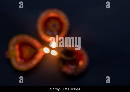 Frohes Diwali. Dimmen Sie drei Ton-Diya-Lampen, die vor schwarzem Hintergrund beleuchtet werden. Hindufest der Lichter. Stockfoto