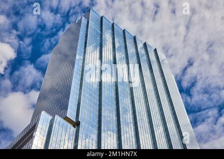 Die Spitze eines großen Glashochkratzers reflektiert den blauen Himmel Stockfoto