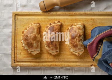 Blick von oben auf gebackene argentinische Empanadas auf einem Brett. Stockfoto