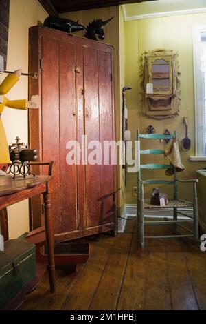 Antike bräunlich rote Holzschränke und dekorative Objekte und Möbel im alten Haus aus dem Jahr 1810 und Antiquitätengeschäft mit breiten Holzdielen. Stockfoto