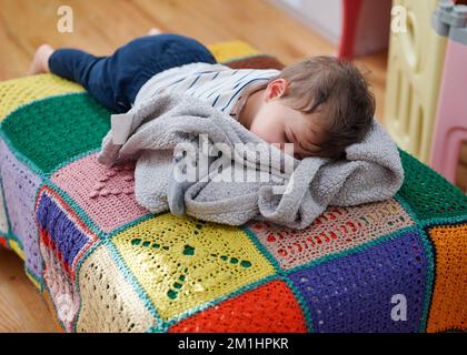 Süßes Kleinkind, das auf einem Futon schläft Stockfoto