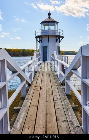 Holzsteg mit weißem Geländer, der zum kleinen Leuchtturm von Maine führt Stockfoto