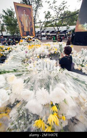 Unbekannte Menschen brachten die Handflächen in Salut, Beten und stellten die Blumen vor das Bild des Königs im Sanam Luang Park in Bangkok. Stockfoto